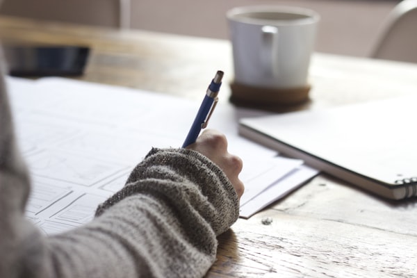 A person researching at a desk with notes and a laptop